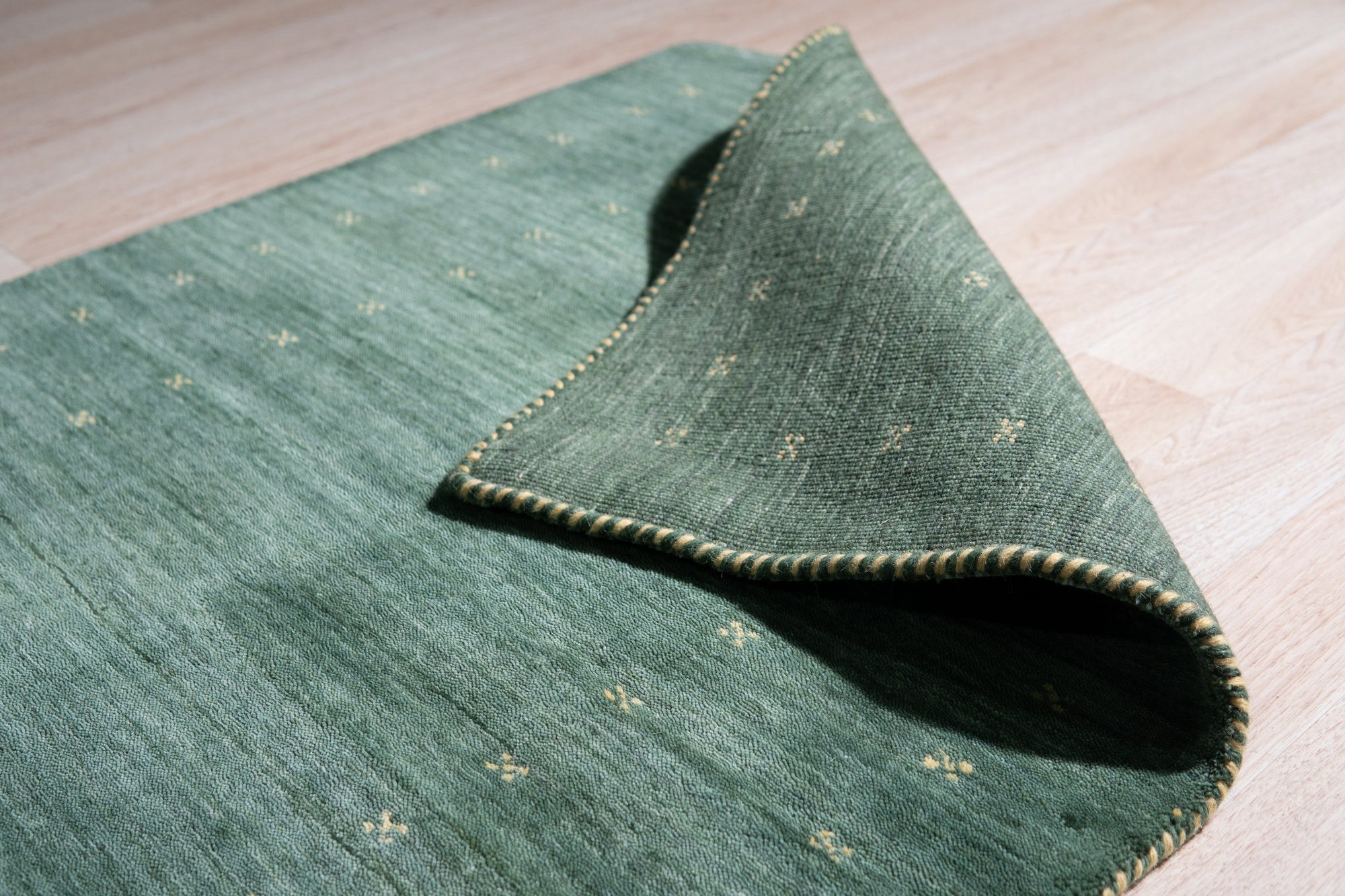 Sloane Ava Green Handmade Wool Rug, its textural surface displaying a subtle, organic pattern in varying shades of green, creating a calming and sophisticated foundation for a contemporary living space.