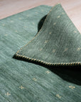 Sloane Ava Green Handmade Wool Rug, its textural surface displaying a subtle, organic pattern in varying shades of green, creating a calming and sophisticated foundation for a contemporary living space.
