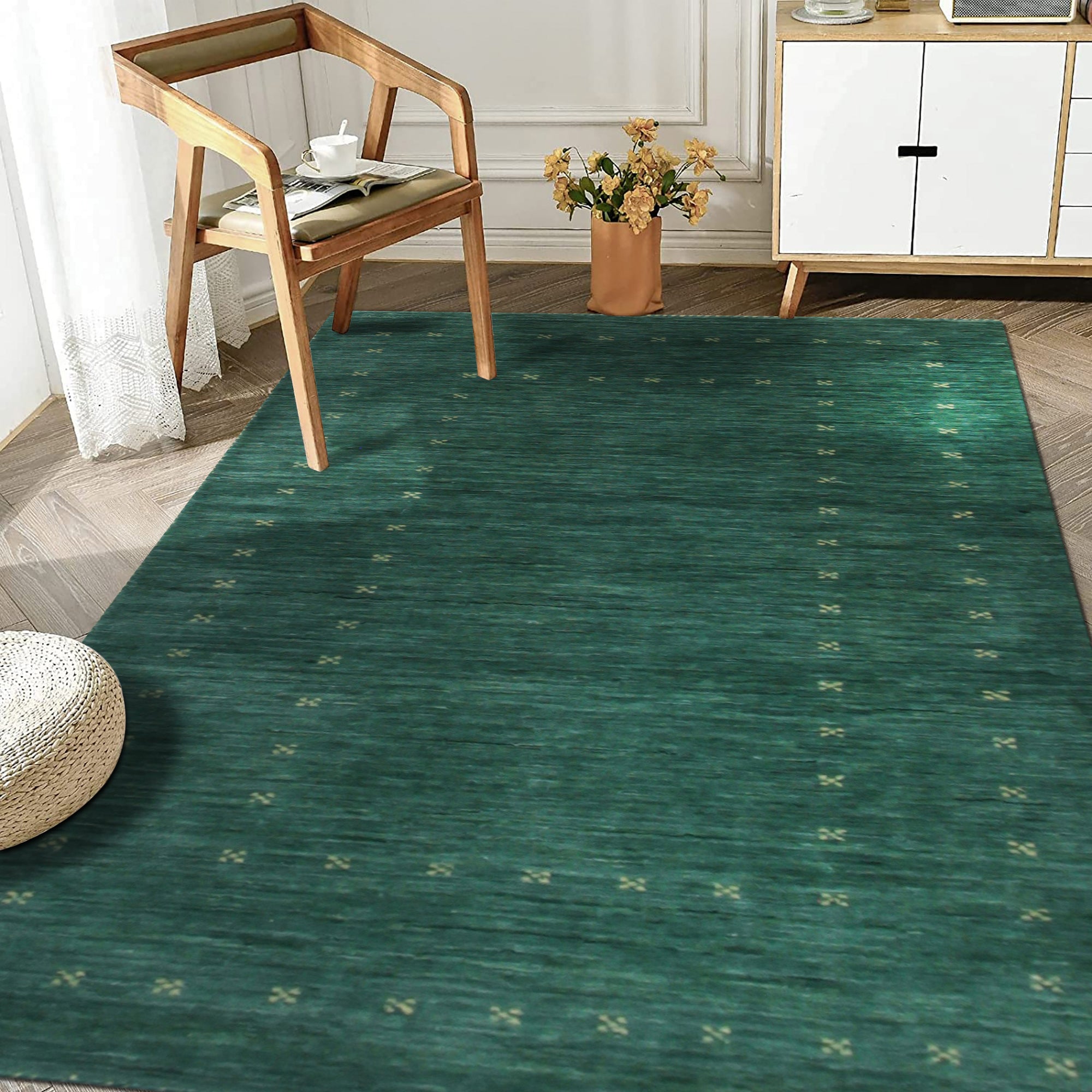 Sloane Ava Green Handmade Wool Rug, luxurious wool floor covering, features a muted green palette with subtle variations, its handmade construction adding depth and texture to a softly lit interior space.