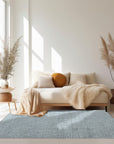 Trendy Dahlia Beige Handmade Wool Rug, a sophisticated neutral rug with a delicate floral dahlia pattern, seen in a bright, modern living room setting.