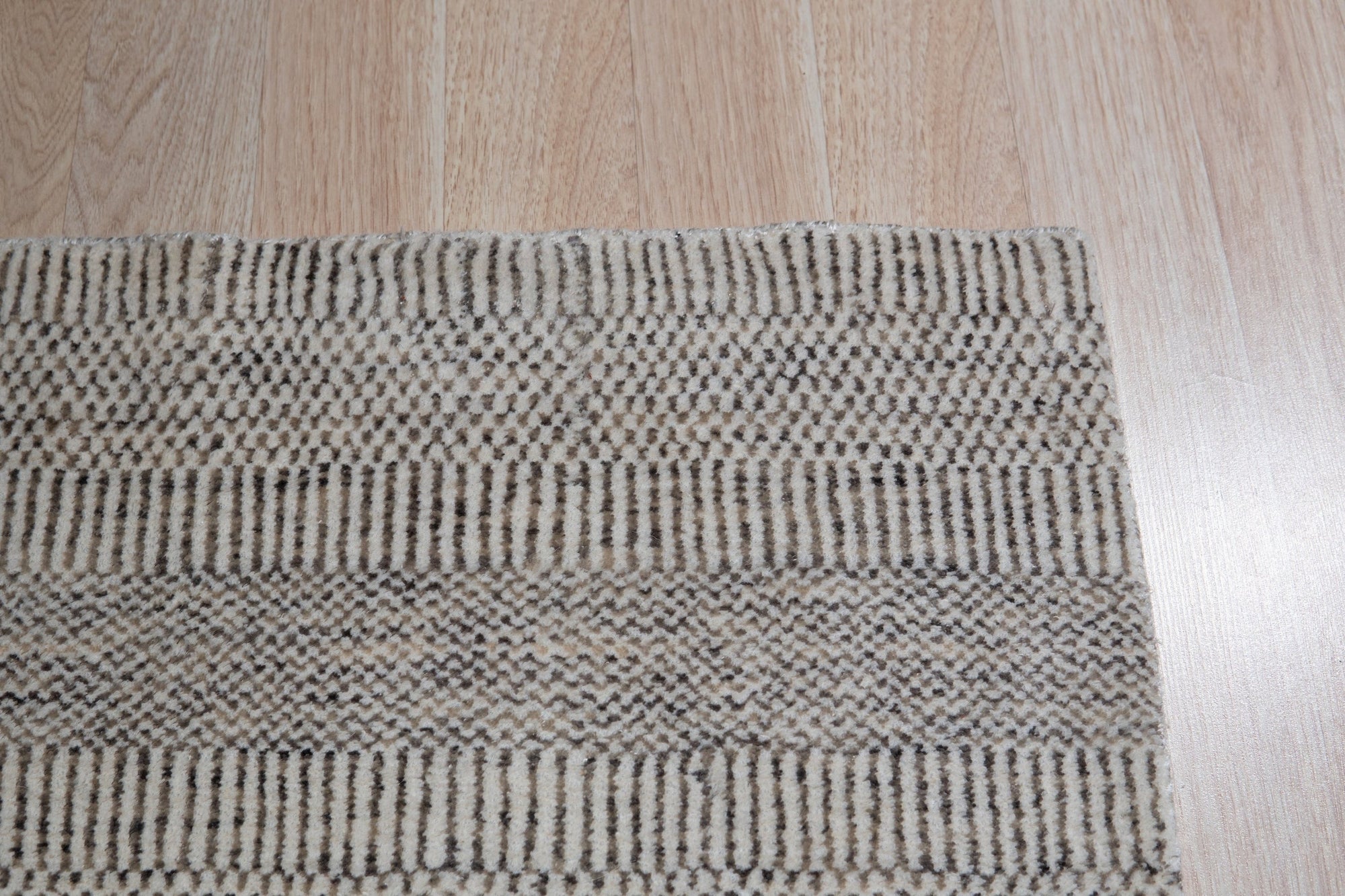 Trendy Dahlia Beige Handmade Wool Rug, showcasing intricate floral patterns in soft beige tones, hand-knotted wool construction brings warmth and texture to a well-lit living space.