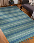 Chic Striped Turquoise Flatweave Wool & Bamboo Silk Rug, its turquoise, cream, and gray stripes adding sophisticated texture to a bright, modern living room.