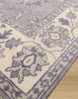 Beautiful Oriental Gray Hand Knotted Wool Rug, its intricate floral medallions and geometric borders rendered in subtle shades of gray and cream, laying elegantly on a polished hardwood floor.