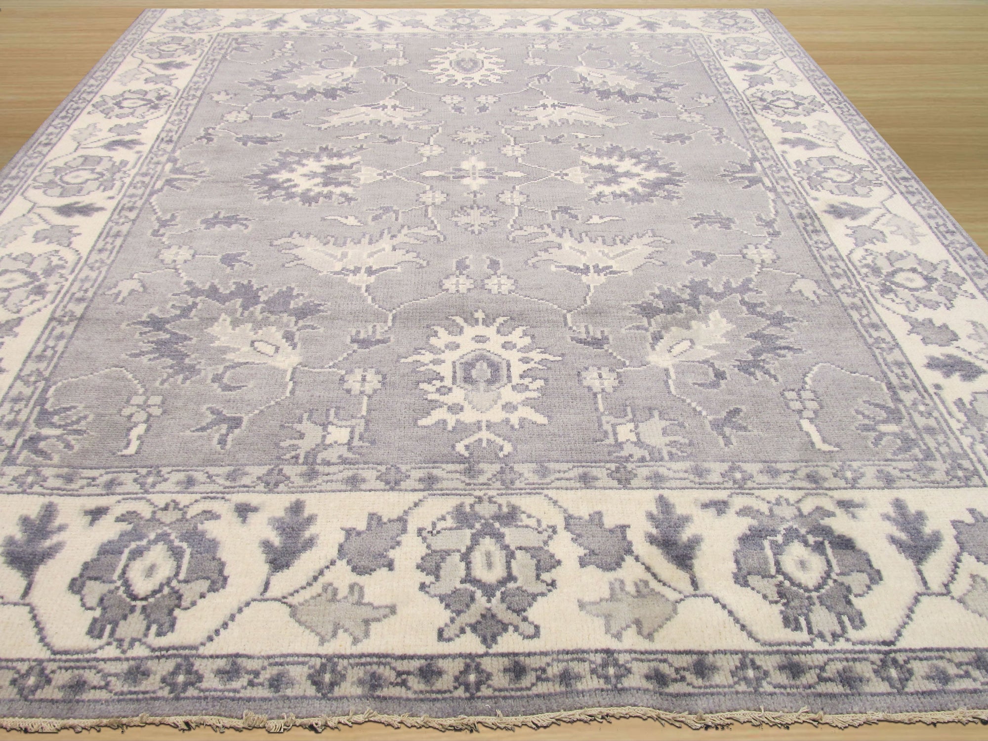 Beautiful Oriental Gray Hand Knotted Wool Rug, its intricate pattern unfolds across a light-filled space. Soft grays and creams interplay on its hand-knotted wool surface, lending a serene elegance to the room.