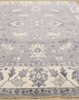 Beautiful Oriental Gray Hand Knotted Wool Rug, its intricate pattern unfolds across a light-filled space. Soft grays and creams interplay on its hand-knotted wool surface, lending a serene elegance to the room.