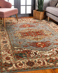 Amara Ruby Blue Hand Knotted Wool Rug displayed on a light hardwood floor, its ruby red and blue hues creating a vibrant contrast. Intricate hand-knotted construction evident in the rug's texture.