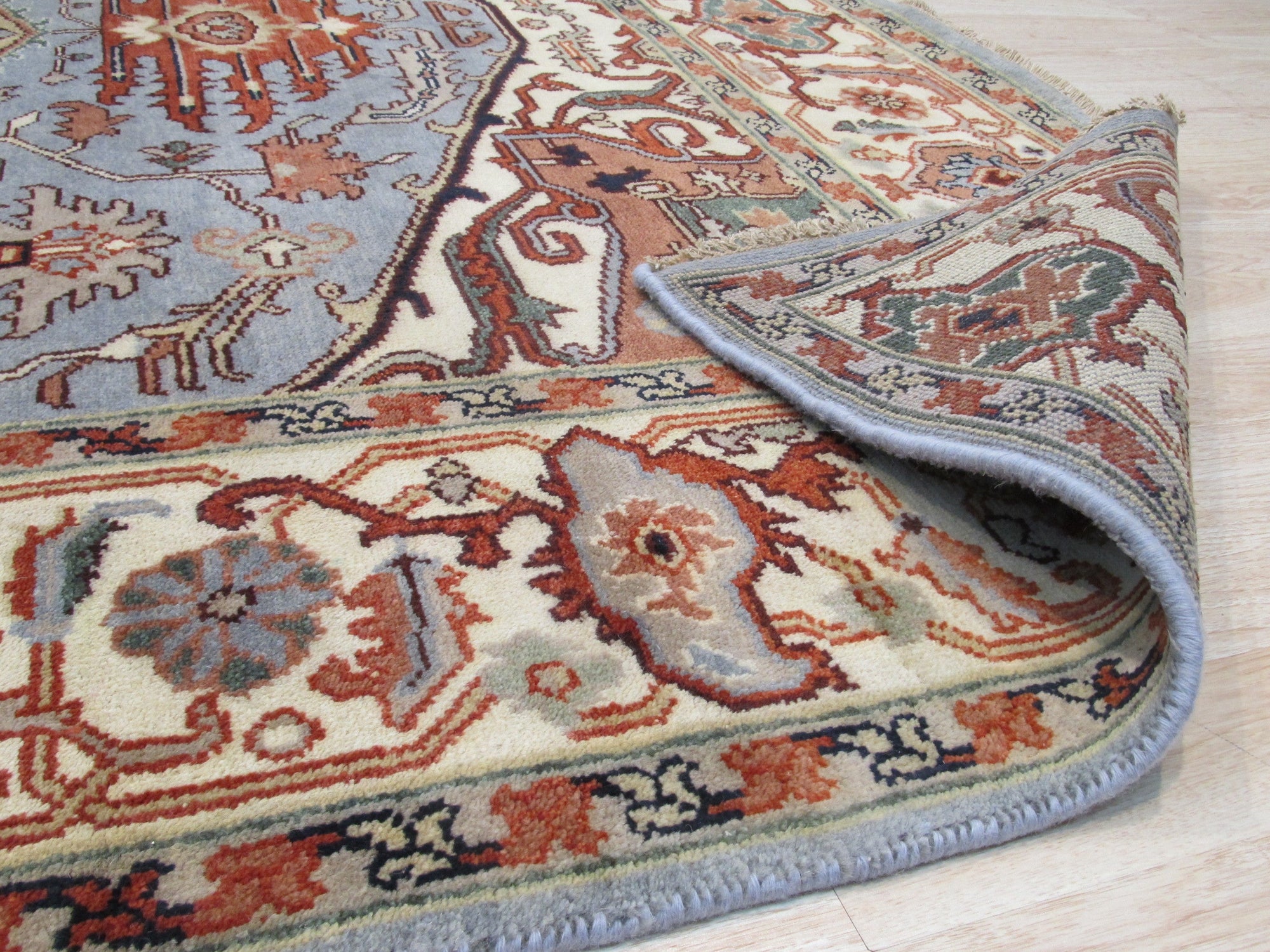 Amara Ruby Blue Hand Knotted Wool Rug, blending ruby reds and blues in a hand-knotted wool construction, displayed in a styled room setting.