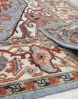 Amara Ruby Blue Hand Knotted Wool Rug, blending ruby reds and blues in a hand-knotted wool construction, displayed in a styled room setting.