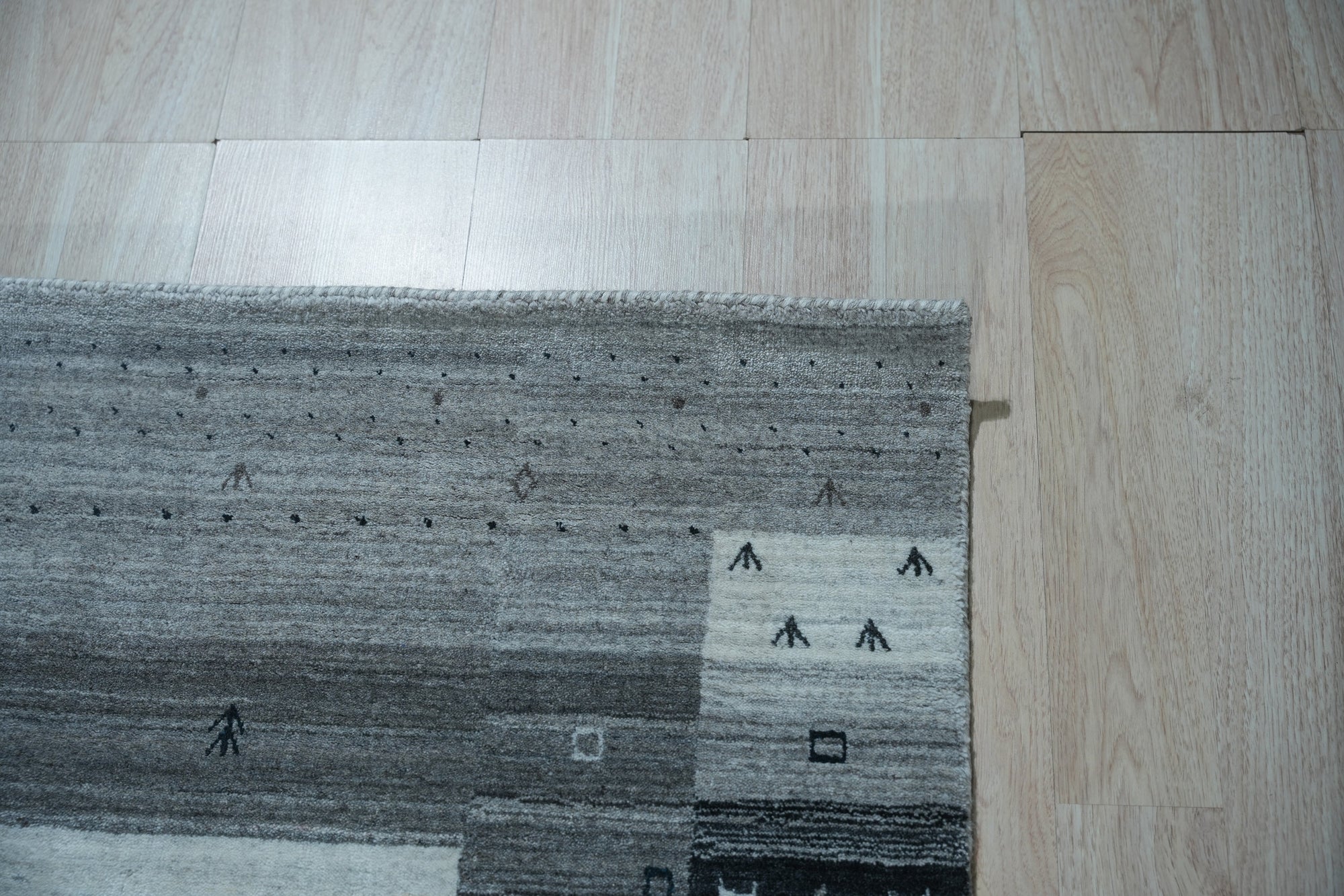 Sophie Gabbeh Gray Handmade Wool Rug, its textured wool pile and minimalist design adding warmth to a brightly lit living room.