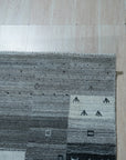 Sophie Gabbeh Gray Handmade Wool Rug, its textured wool pile and minimalist design adding warmth to a brightly lit living room.