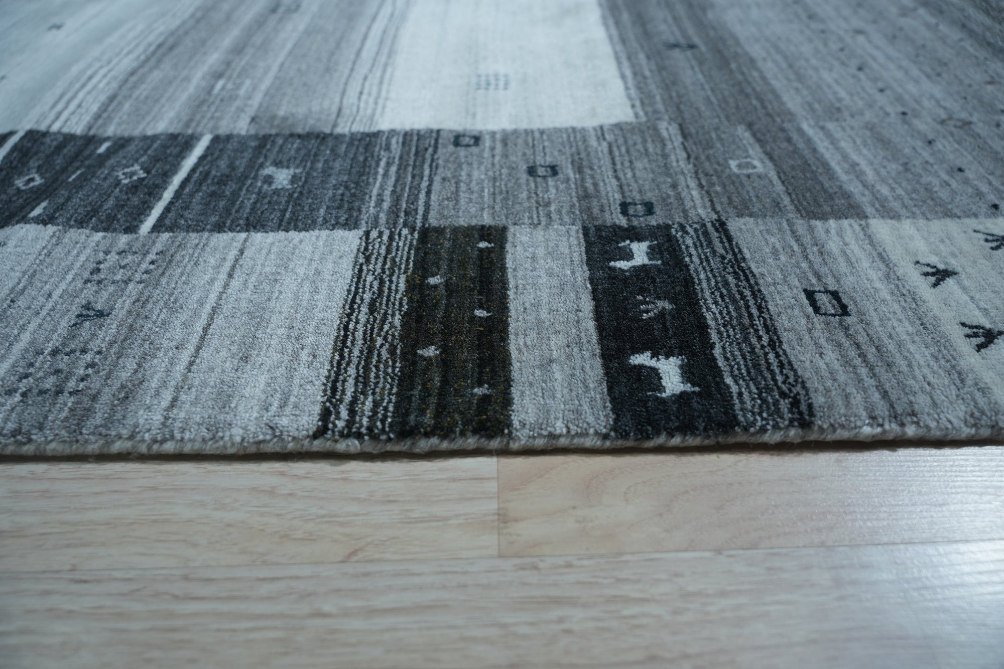 Sophie Gabbeh Gray Handmade Wool Rug displayed in a bright living room setting. Gray tones and subtle textural variations create a warm, inviting feel. Handcrafted wool construction evident in the rug's dense pile.
