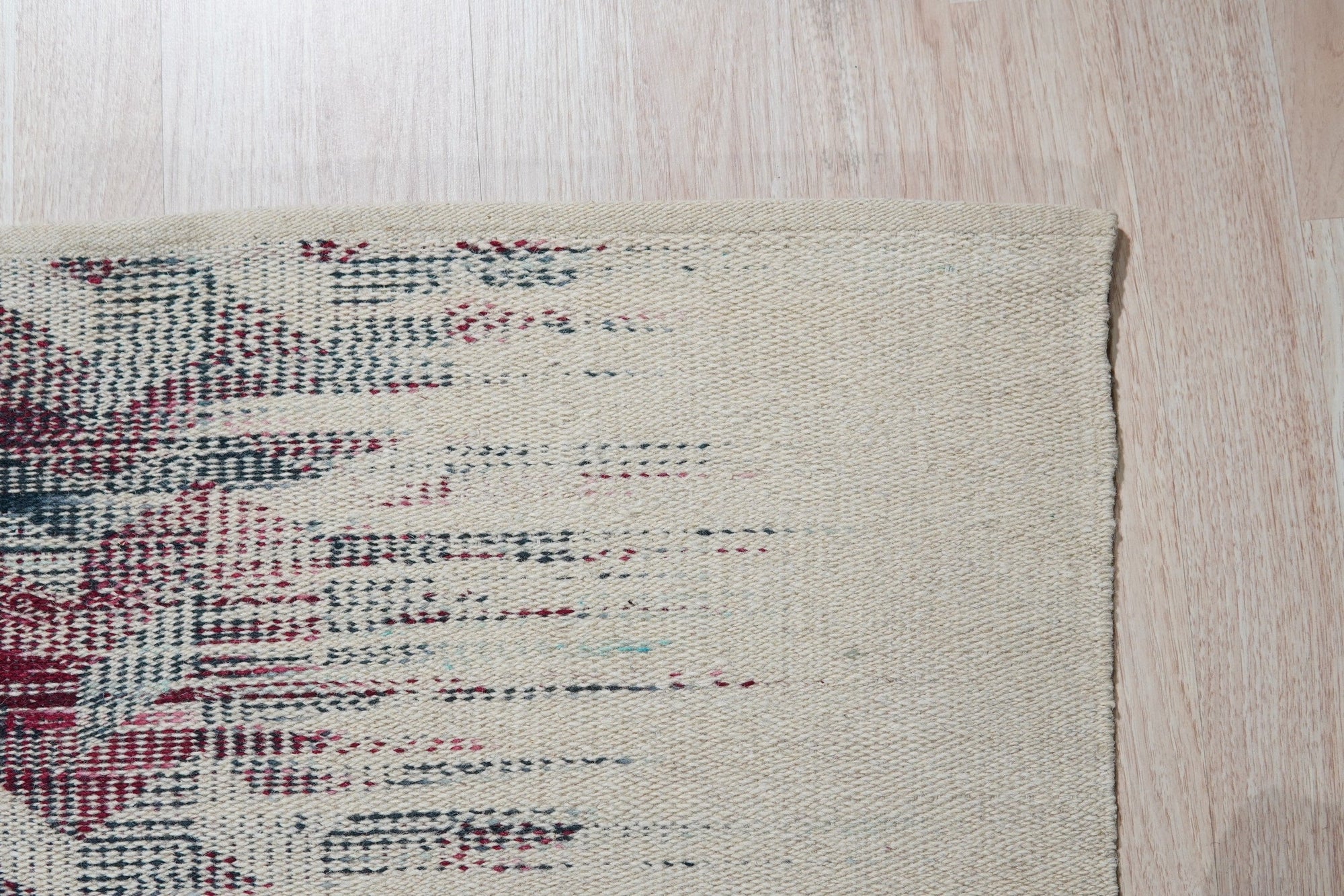Brenda Refined Multicolor Flatweave Wool Rug, showcasing vibrant hues and a geometric pattern, lies flat on a hardwood floor, its texture suggesting soft wool construction.
