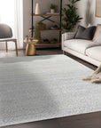 Bianca Louie Ivory Handmade Wool Rug, seen in a styled room setting, showcases its luxurious texture and subtle pattern under a modern coffee table with decorative books and objects. The soft ivory tones and hand-knotted wool construction create a warm and inviting atmosphere.