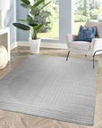 Majestic Chic Charcoal Handmade Wool Rug, charcoal tones and subtle textures define this wool rug, nestled within a bright, modern living room with natural light highlighting its hand-knotted construction and adding warmth to the space.