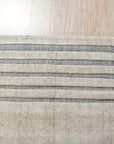 Majestic Chic Charcoal Handmade Wool Rug displayed on a light wooden floor, showcasing its deep charcoal hues and textured, hand-woven wool construction. Subtle pattern emerges from the pile in a modern, abstract design.