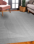 Majestic Chic Charcoal Handmade Wool Rug, charcoal textured wool rug with subtle pattern variations across its surface, seen in a warm-toned living room setting.