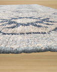 Para Giselle Blue Hand Knotted Rug, showcasing a complex geometric pattern in varying shades of blue and ivory, lies on a light hardwood floor, creating a sophisticated and inviting living space.