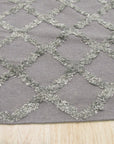 Nina Marrakesh Dark Gray Hand Knotted Wool & Viscose Rug, blending dark gray tones in a hand-knotted construction, displayed on a light hardwood floor and partially covered by a modern gray sofa.