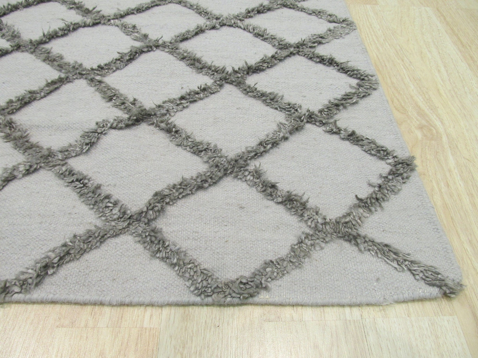 Maya Trellis Gray Hand Knotted Wool & Viscose Rug, showcasing its delicate trellis design in varying shades of gray, lending sophisticated texture and subtle sheen to the room.