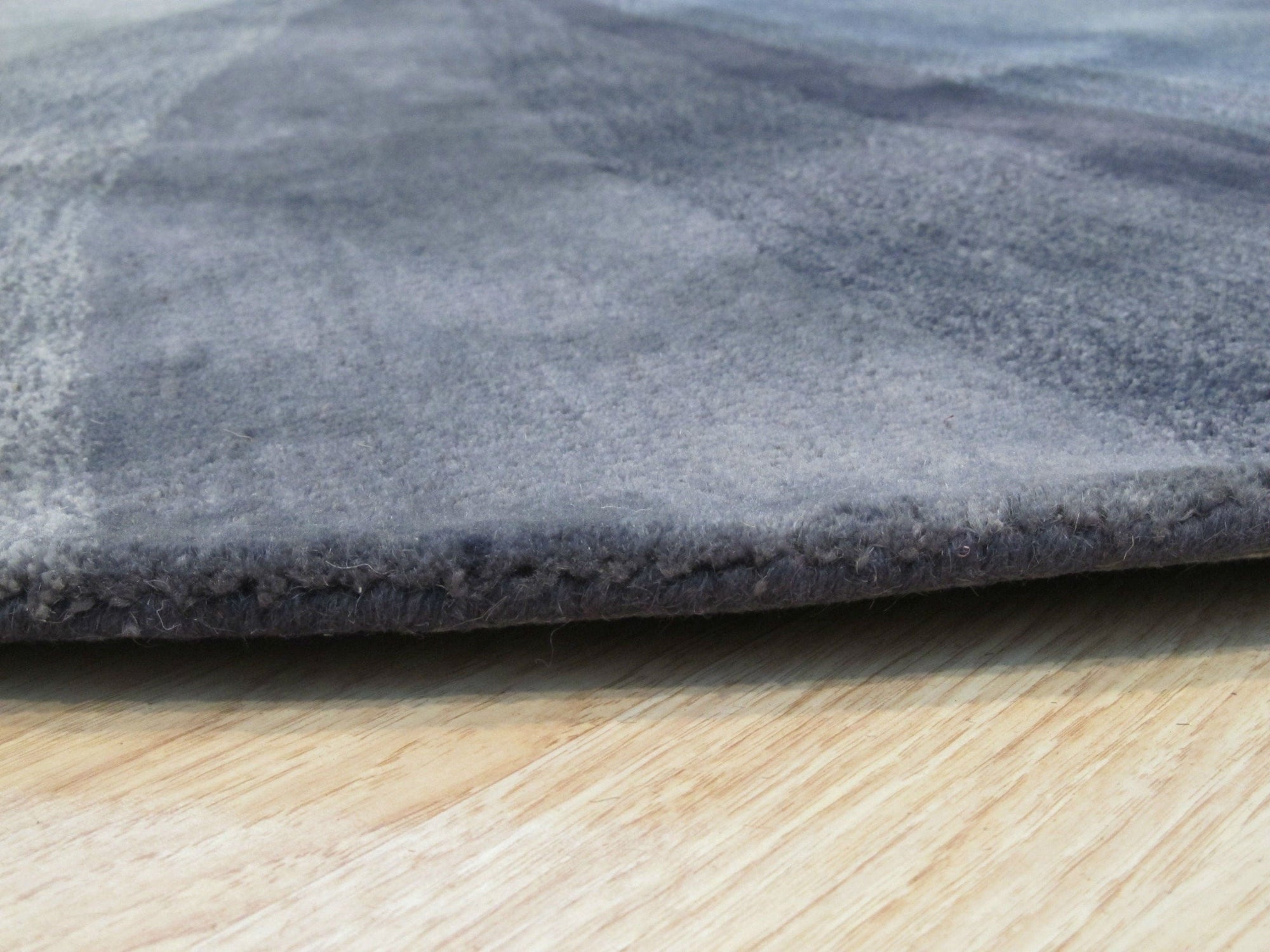 Stylish Timeless Blue Hand Tufted Wool Rug, showcasing its deep blue hue and textured hand-tufted wool construction, lies flat against a light-toned floor, its circular shape filling the frame.