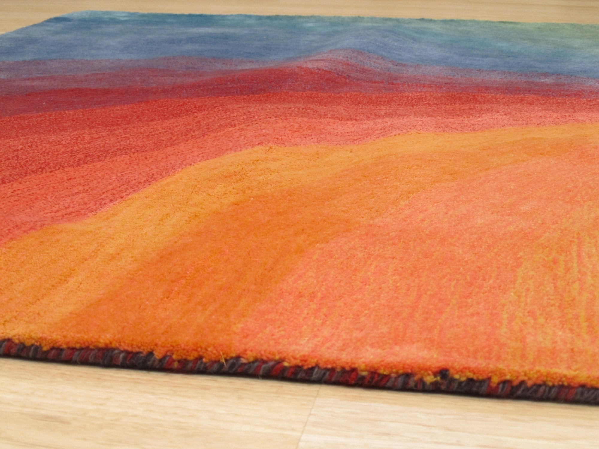 Talia Classic Rainbow Hand Tufted Wool Rug, vibrant waves of color arch across a plush wool surface, hand-tufted for a luxuriously textured feel, displayed amidst soft, natural lighting.