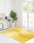 Brenda Chic Yellow Hand Tufted Wool Rug, radiating warmth and texture in a brightly lit interior. Its hand-tufted wool construction showcases subtle variations in the sunny yellow hue, complemented by a minimalist, chic design.