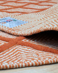 Refined Luxurious Orange Handmade Wool Rug, vibrant orange wool adding warmth to a room with neutral furniture; intricate, possibly hand-knotted construction visible in detail.