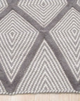 Trendy Diamond Gray Hand Knotted Wool Rug, its muted gray tones and diamond pattern subtly enhance a modern living room, seen under warm ambient light accentuating the rug's hand-knotted texture.
