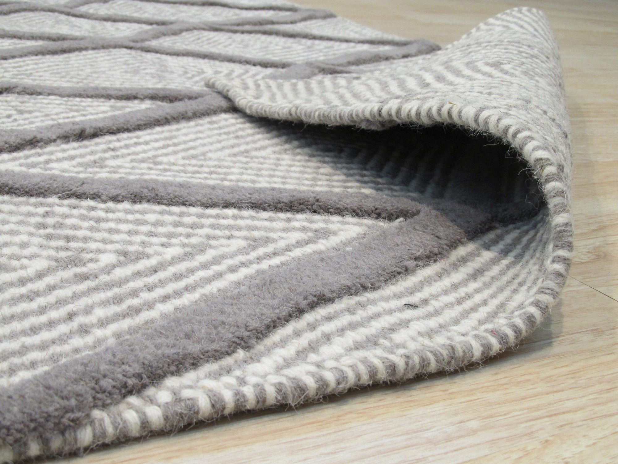 Trendy Diamond Gray Hand Knotted Wool Rug, its geometric diamond pattern subtly textured and displayed on a hardwood floor in a living room setting.