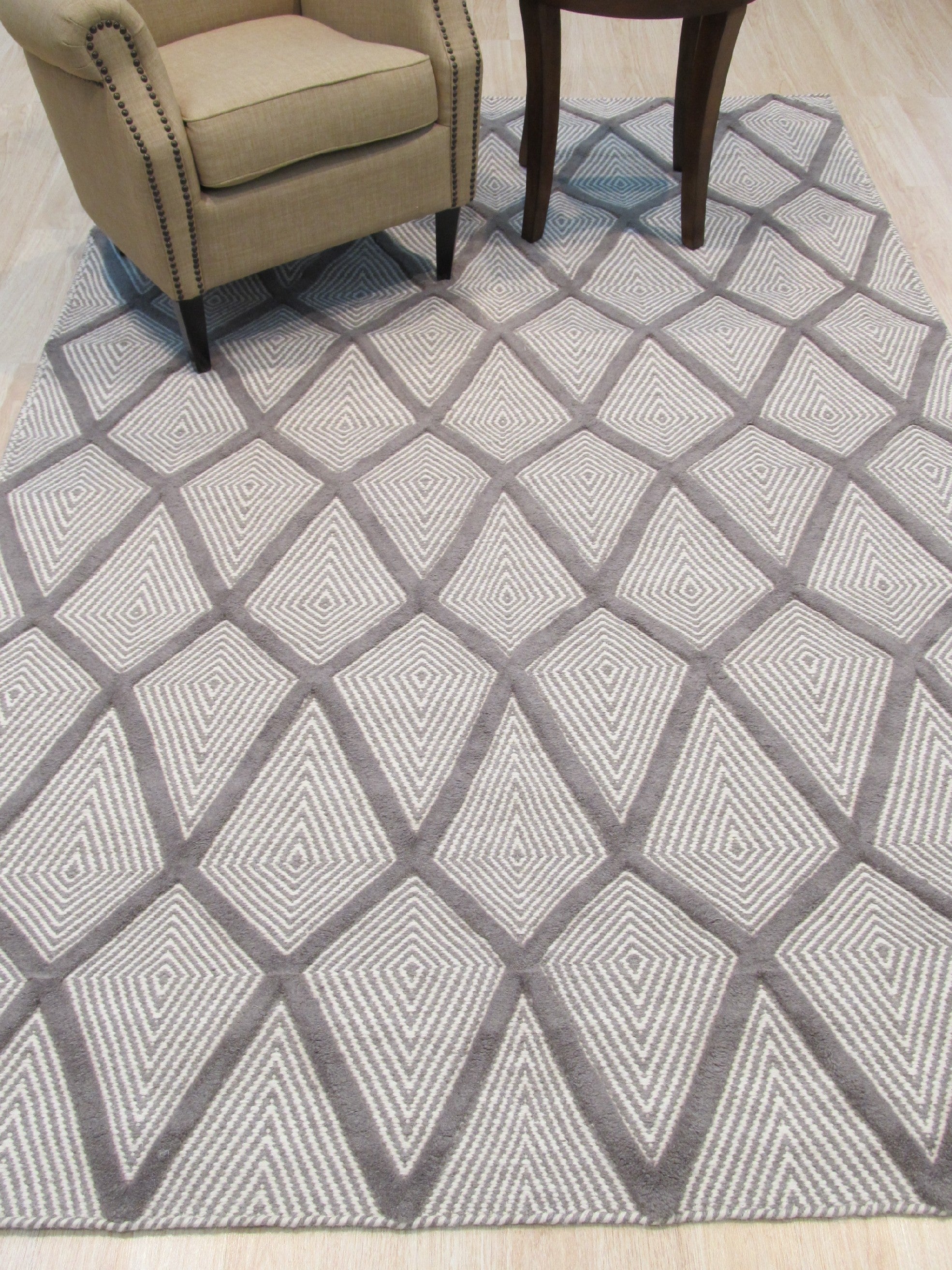 Trendy Diamond Gray Hand Knotted Wool Rug, soft gray and ivory diamonds dance across a hand-knotted wool rug, lending subtle texture and modern elegance to a warmly lit living space.