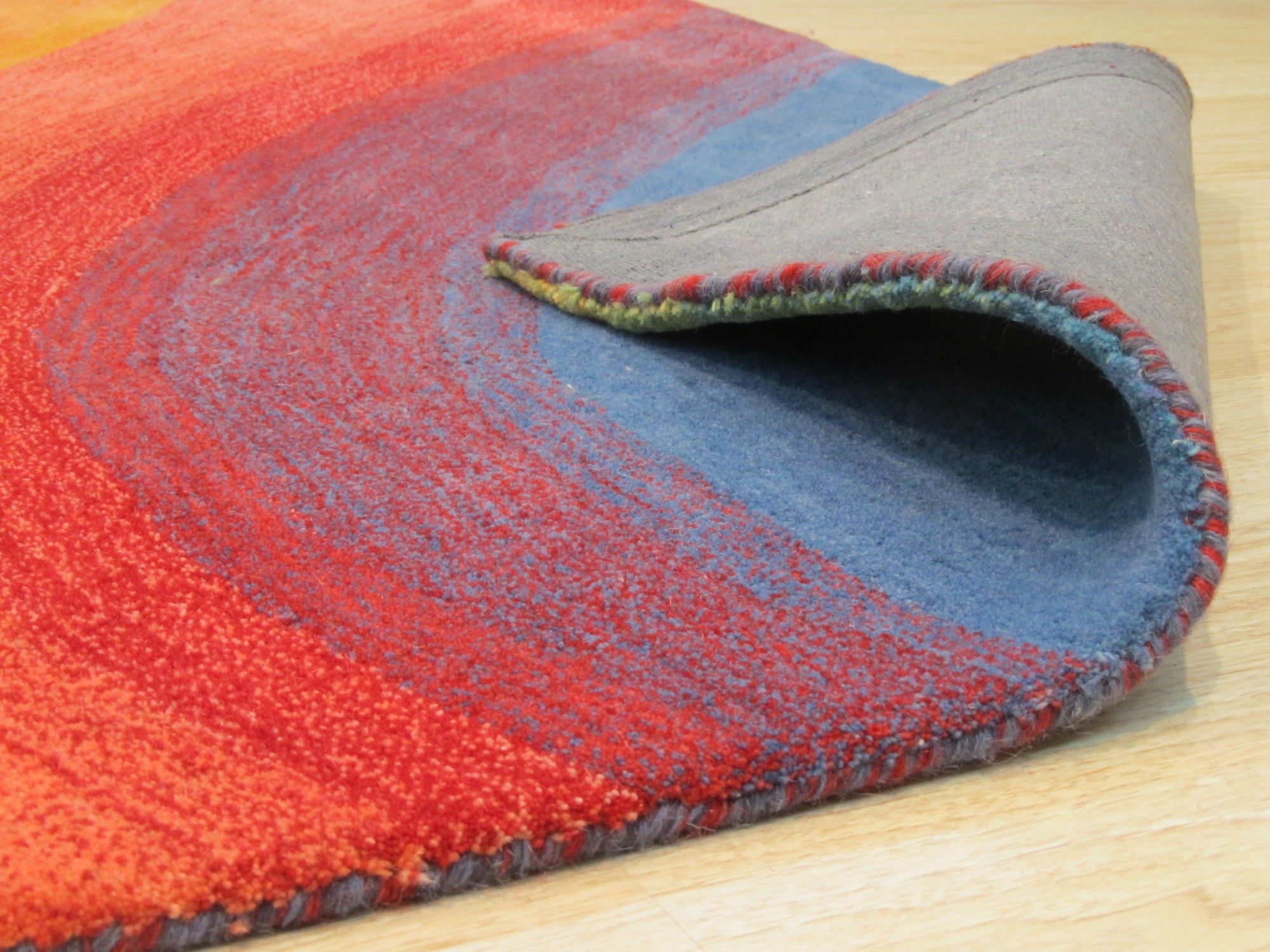 Vibrant Dazzling Multicolor Hand Tufted Wool Rug, bursting with energetic hues and tactile textures, sits atop a polished hardwood floor. Multicolor blocks in shades of orange, teal, pink, and yellow create a playful, modern grid pattern in this hand-tufted wool rug.