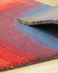 Vibrant Dazzling Multicolor Hand Tufted Wool Rug, bursting with energetic hues and tactile textures, sits atop a polished hardwood floor. Multicolor blocks in shades of orange, teal, pink, and yellow create a playful, modern grid pattern in this hand-tufted wool rug.