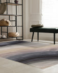 Xena Violet Blue Hand Tufted Wool Rug displayed on a light hardwood floor, its violet and blue hues creating a soothing and sophisticated palette. The rug's hand-tufted construction adds texture and depth to its design, complementing the room's warm, inviting atmosphere.