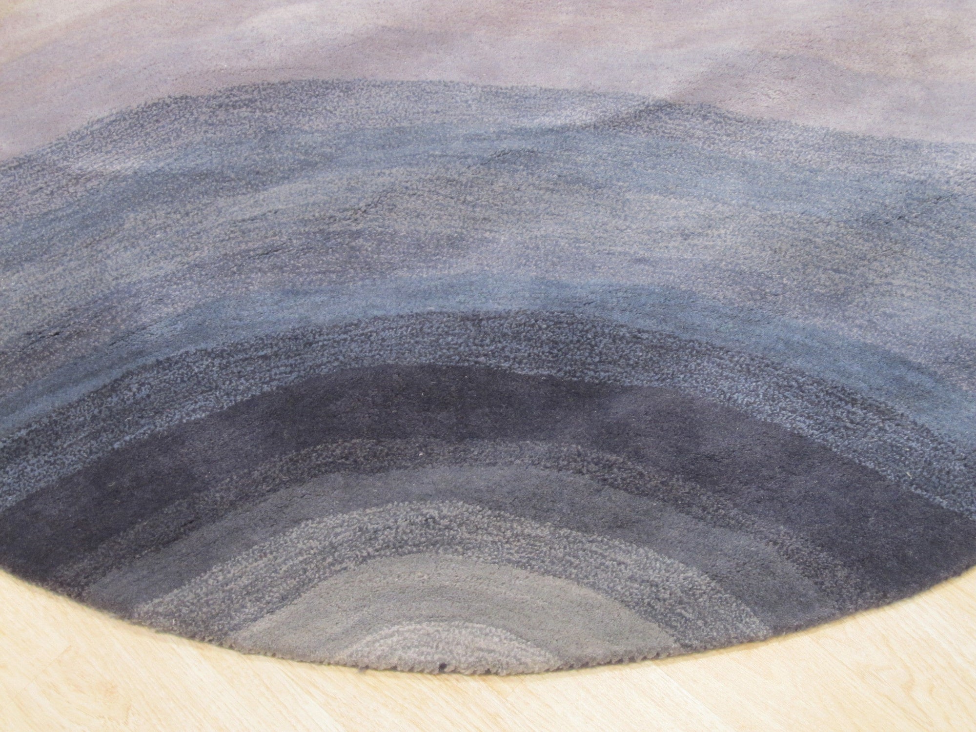 Xena Violet Blue Hand Tufted Wool Rug, a vibrant blend of violet and blue hues in a hand-tufted wool construction, displayed in a stylish home setting.