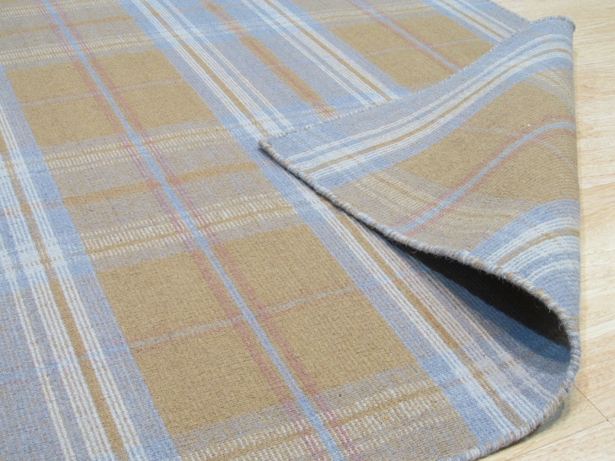 Sarrah Delicate Gold Flatweave Wool Rug displayed in a bright, airy living space. The rug's subtle gold tones and flatweave construction complement the modern décor, adding warmth and texture to the room.