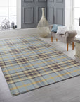 Jade Dahlia Blue Flatweave Wool Rug, showcasing a detailed dahlia-inspired design in shades of blue, gray, and cream, laid on a light wooden floor. Warm sunlight illuminates the rug's flatweave construction and intricate floral pattern, creating a serene and inviting atmosphere.