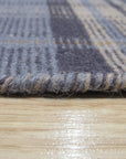 Jade Dahlia Blue Flatweave Wool Rug, its dahlia floral pattern unfolding in shades of blue across a flatweave wool construction, filling a modern living room with serene color.