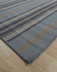Jade Dahlia Blue Flatweave Wool Rug, seen in a brightly lit room, features a complex dahlia-inspired pattern in shades of blue on a light background. The flatweave construction is visible, offering a textural element.