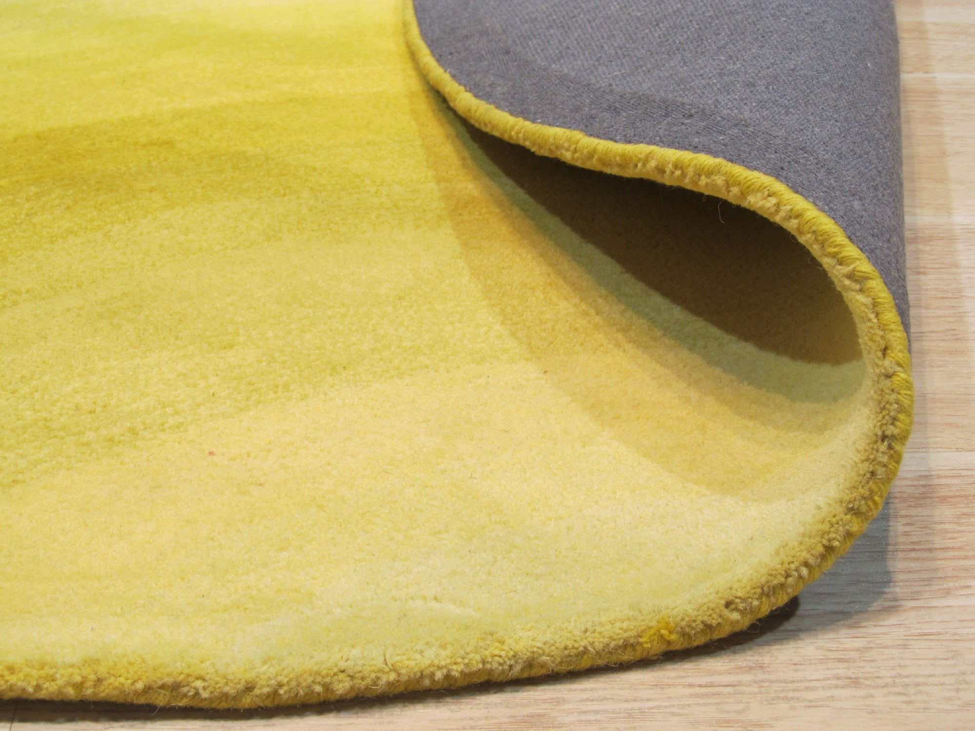 Inviting Ruby Yellow Hand Tufted Wool Rug, featuring swirling patterns in shades of ruby red and golden yellow, covers the floor, adding warmth and texture to a modern living space.