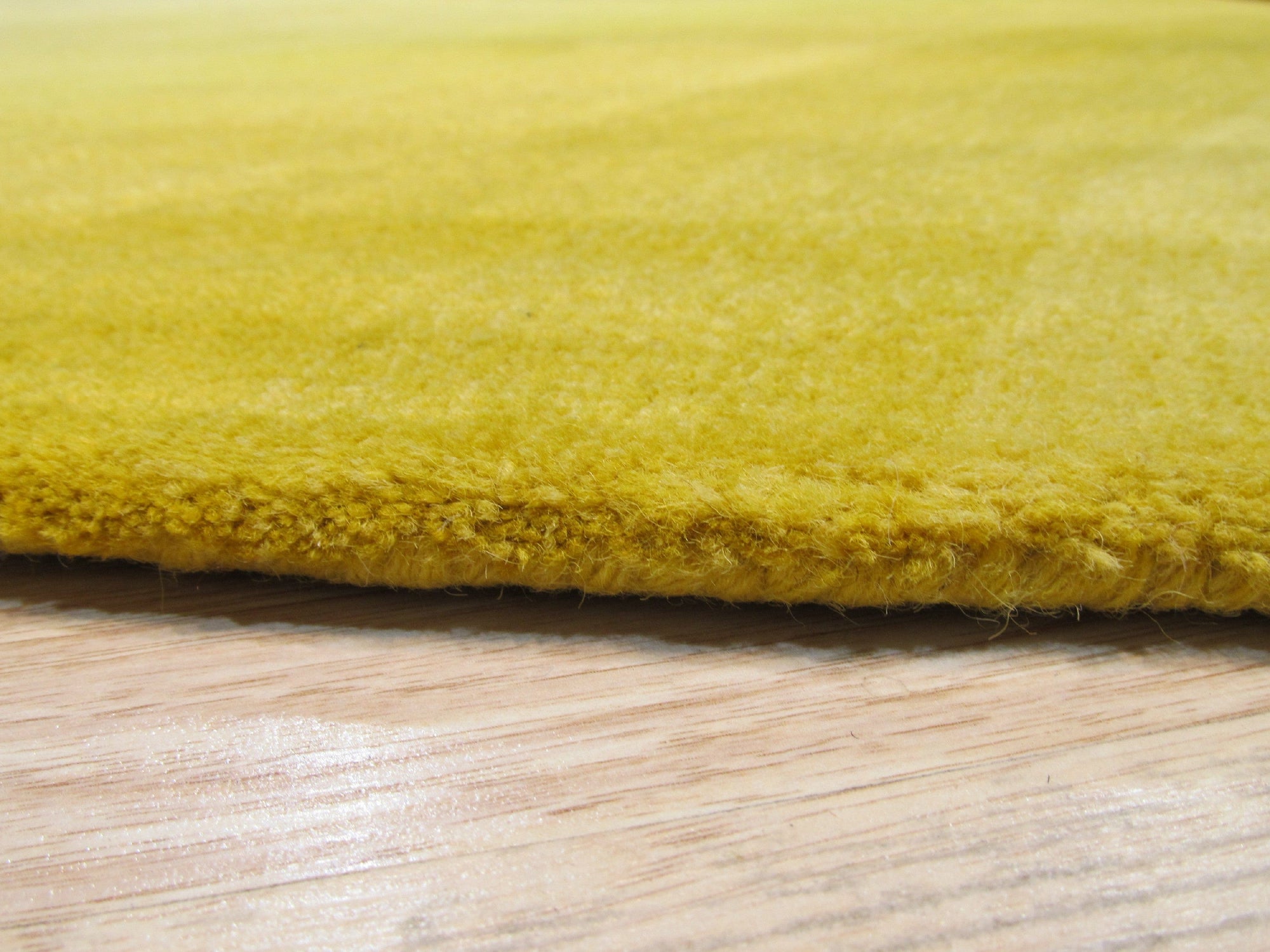 Inviting Ruby Yellow Hand Tufted Wool Rug, its warm ruby and yellow hues radiating from a densely tufted wool pile, sits elegantly on a light hardwood floor.