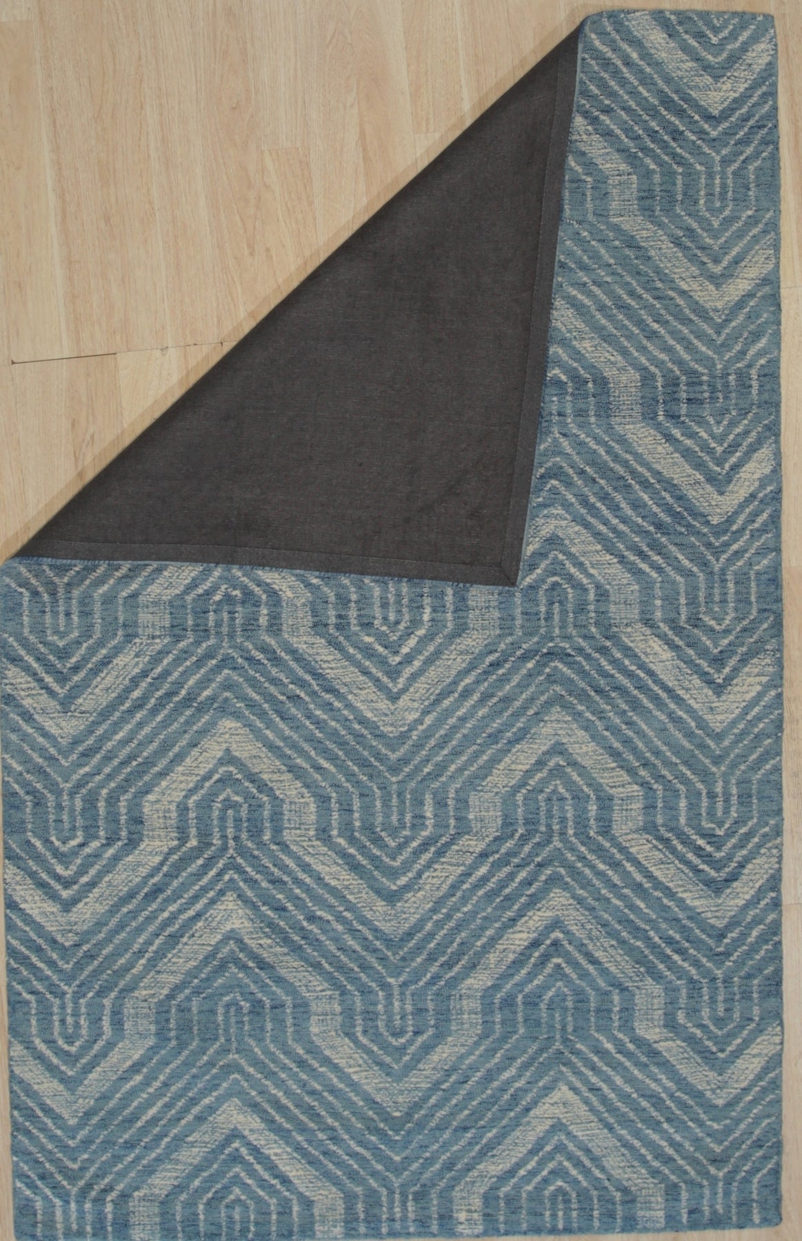 Lila Dahlia Blue Hand Tufted Wool Rug, a deep blue wool rug with a stylized floral dahlia design, displayed in a bright, modern living room setting.