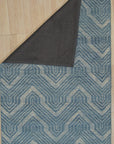 Lila Dahlia Blue Hand Tufted Wool Rug, a deep blue wool rug with a stylized floral dahlia design, displayed in a bright, modern living room setting.