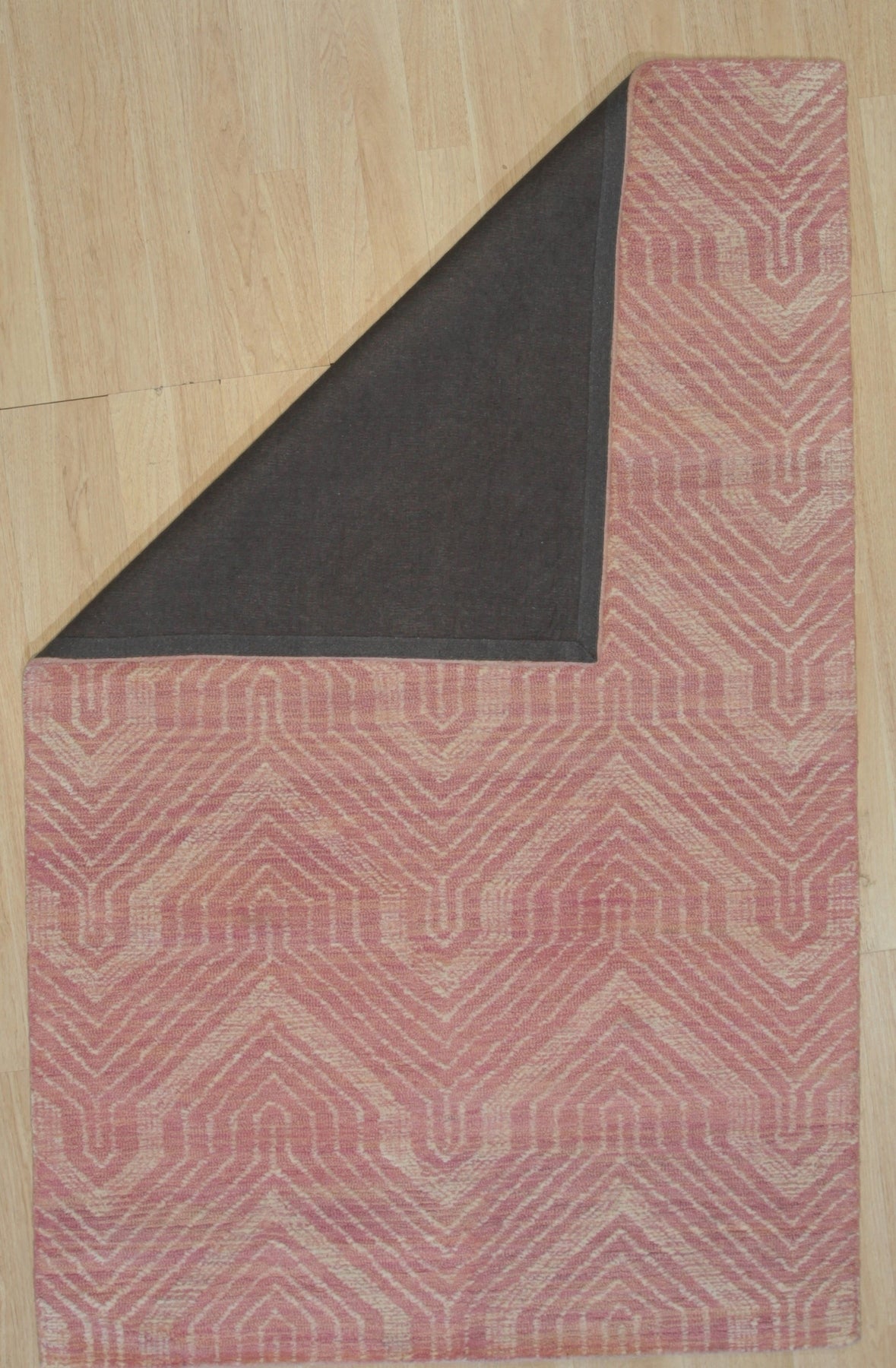 Maya Lush Pink Hand Tufted Wool Rug, a soft and textured wool rug in a vibrant blush pink, lies flat on a light surface. Its hand-tufted construction creates a plush pile, inviting touch and adding a warm accent.