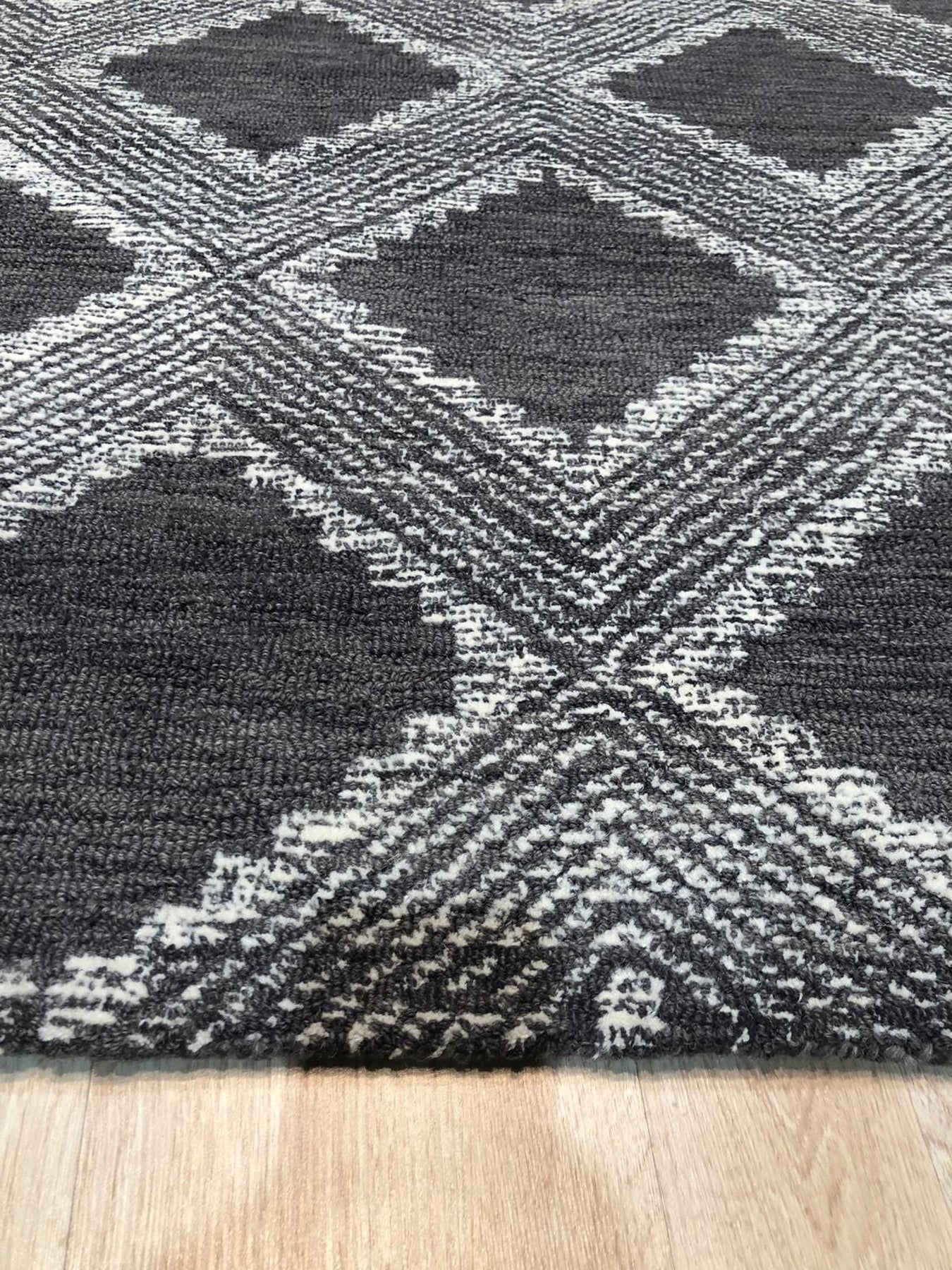 Xena Ava Charcoal Hand Tufted Wool Rug, hand-tufted wool construction with a deep charcoal hue, displayed in a bright, modern living room setting with minimalist decor.