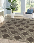 Xena Ava Charcoal Hand Tufted Wool Rug, a deep charcoal wool rug with subtle textural variations, partially visible in a warm, inviting living room setting.