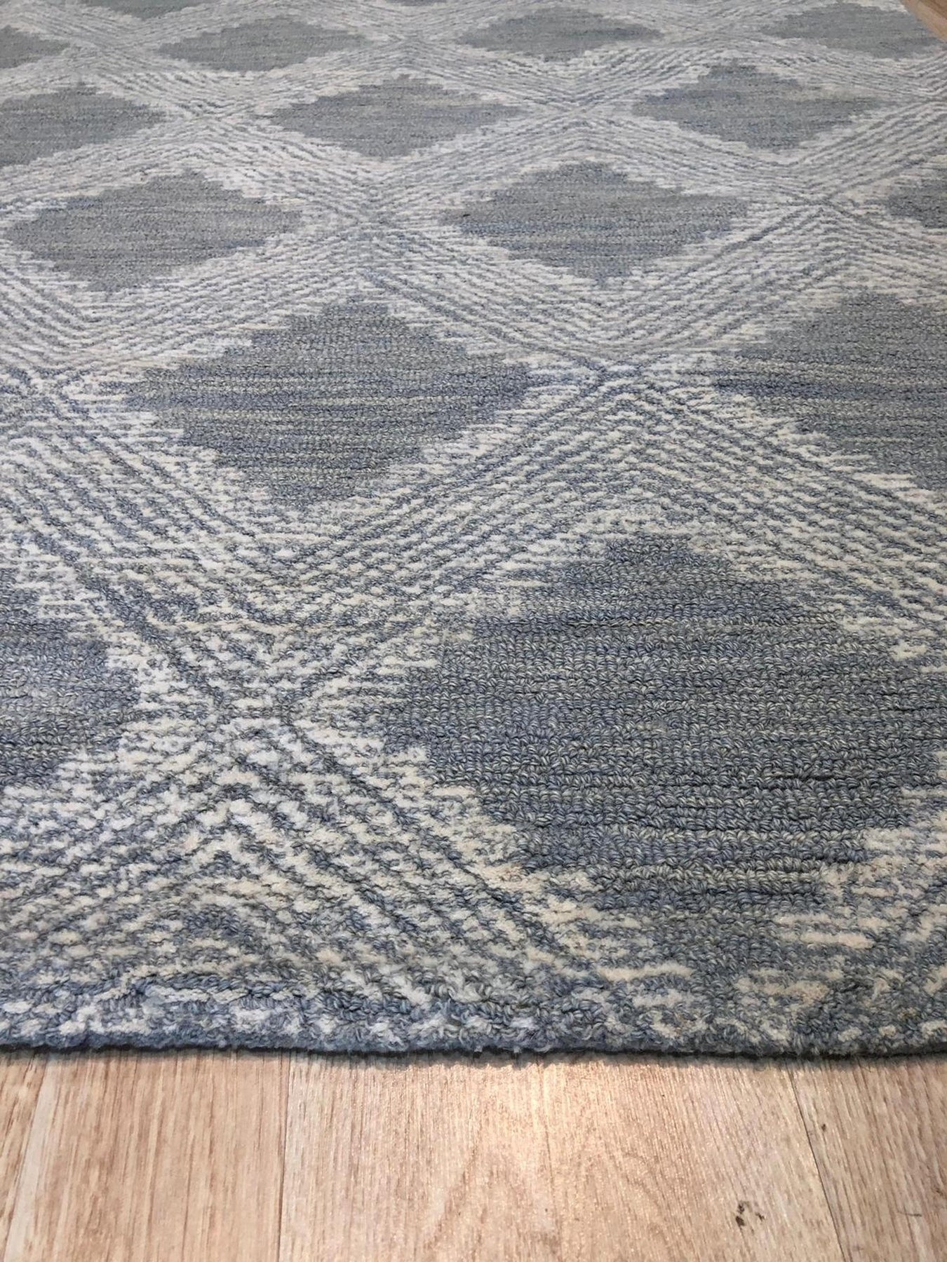 Chloe Quinn Light Blue Hand Tufted Wool Rug, soft light blue tones and hand-tufted wool texture create a calming atmosphere in a warmly lit room.