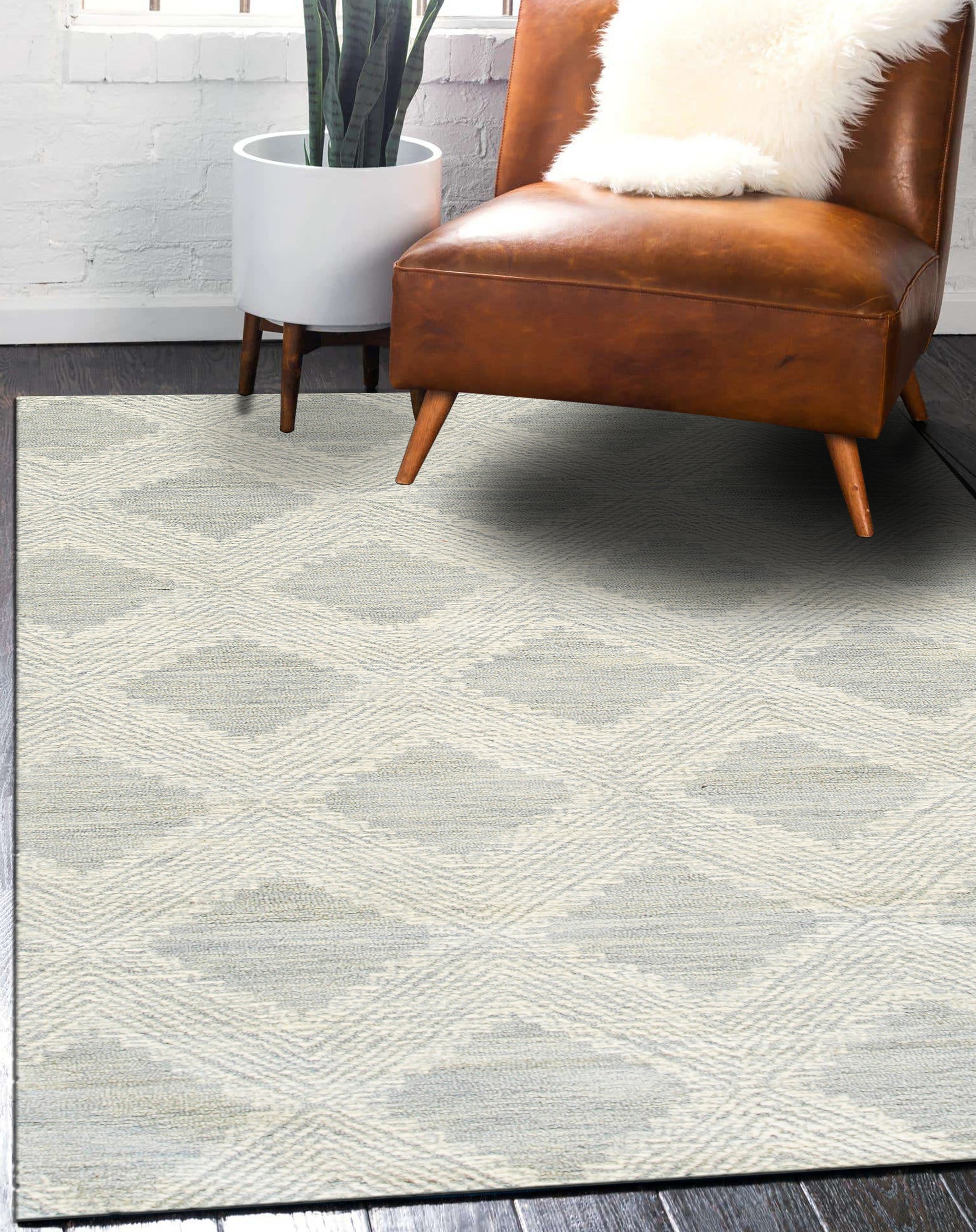 Chloe Quinn Light Blue Hand Tufted Wool Rug, its delicate patterns unfurling in soft blues and creams, lying gracefully on a light hardwood floor in a naturally lit room.