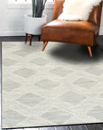 Chloe Quinn Light Blue Hand Tufted Wool Rug, its delicate patterns unfurling in soft blues and creams, lying gracefully on a light hardwood floor in a naturally lit room.
