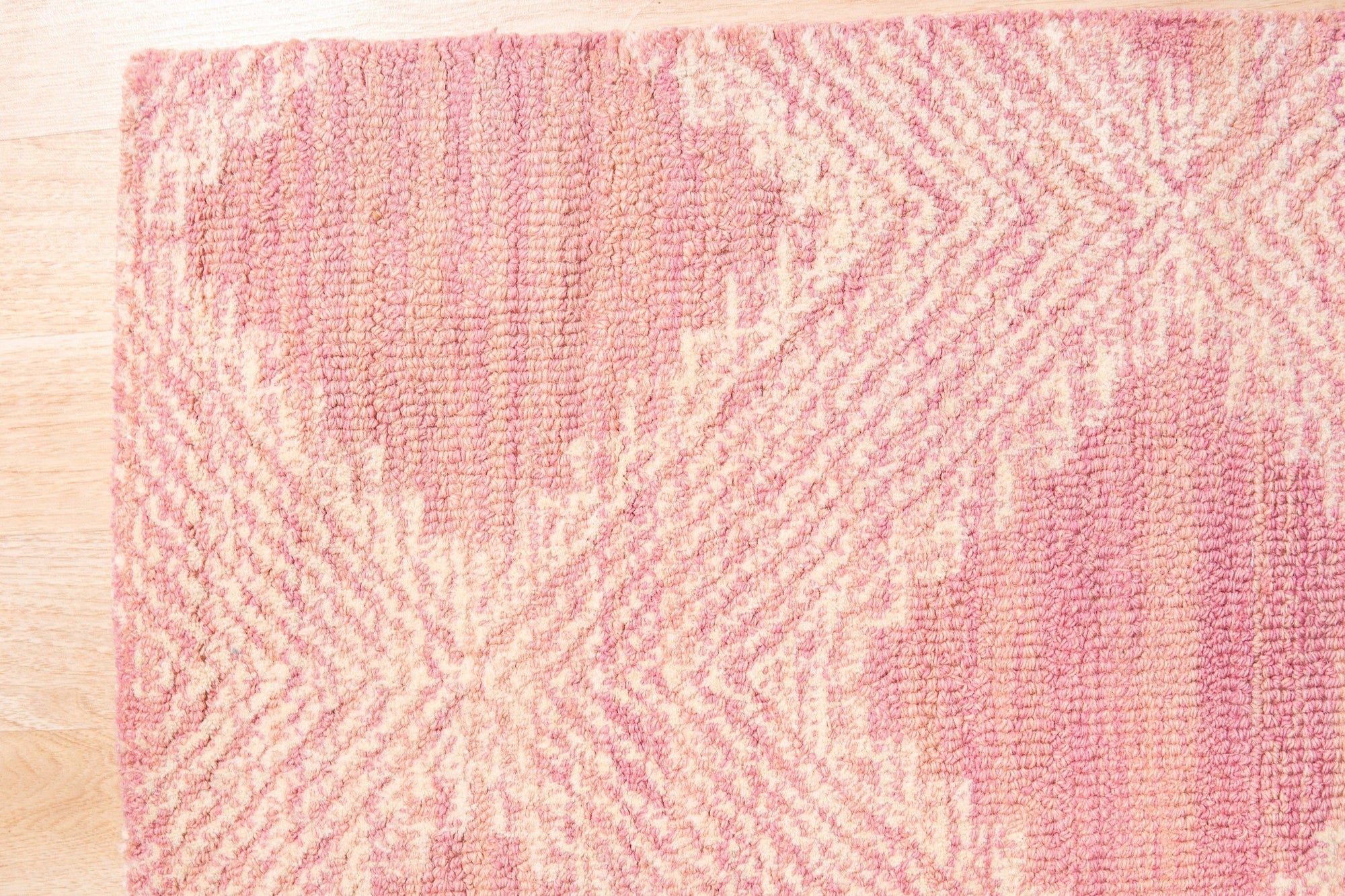 Unique Sloane Pink Hand Tufted Wool Rug, a soft blush-pink wool rug with a subtle geometric pattern, displayed in a bright, modern living space.