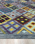 Nadia Kilim Multicolor Flatweave Wool Rug, displaying vibrant hues and geometric patterns, lying flat on a light surface, showcasing its texture and detailed weave.